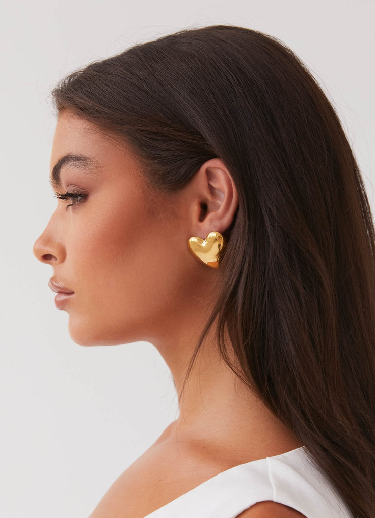 Womens Alexa Heart Earrings in the colour Gold in front of a light grey background