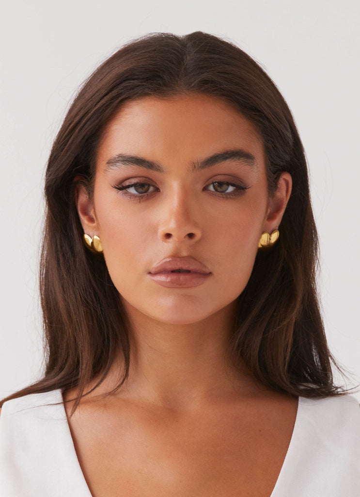 Womens Alexa Heart Earrings in the colour Gold in front of a light grey background