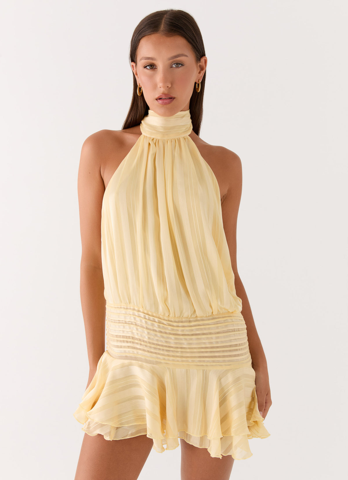Editorial styling image of a yellow pleated chiffon halter mini dress
