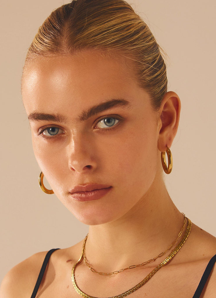 Womens Keep Frontin Hoop Earrings in the colour Gold in front of a light grey background